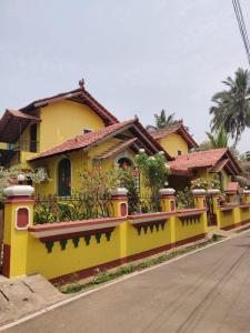 a yellow house with a yellow and red fence at Villa Agastya in Betalbatim
