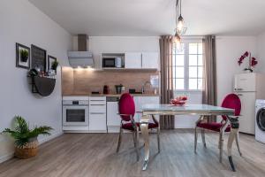 a kitchen with a table and two pink chairs at Suite L'echappee - Maison romantique - SPA & Sauna Privatif- Pole Dance - Lit rond avec miroir au plafond in Pézarches