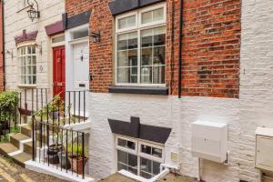 a brick building with a red door and windows at Anchor Cottage in Whitby