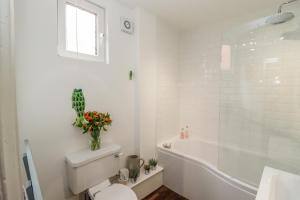 a white bathroom with a toilet and a bath tub at Anchor Cottage in Whitby +23 photos