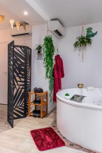 baño con bañera blanca y alfombra roja en Suite L'echappee - Maison romantique - SPA & Sauna Privatif- Pole Dance - Lit rond avec miroir au plafond, en Pézarches