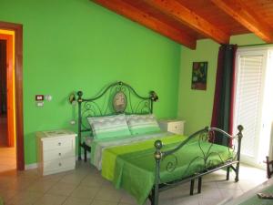zieloną sypialnię z łóżkiem i zieloną ścianą w obiekcie B&B Le Terrazze Isola Di S. Antioco w mieście SantʼAntìoco