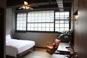 a bedroom with a bed and a desk and a window at The Retro Tai-Pan in Tainan