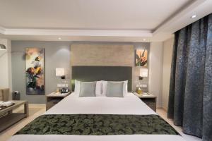 a bedroom with a large white bed and two tables at Centara Muscat Hotel Oman in Muscat