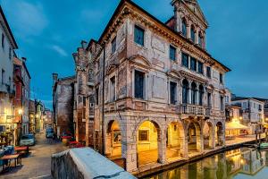 an old building next to a canal at night at Piccola Venezia Room in Chioggia