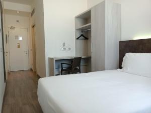 sypialnia z dużym białym łóżkiem i biurkiem w obiekcie Phi Hotel Milano w mieście Baranzate