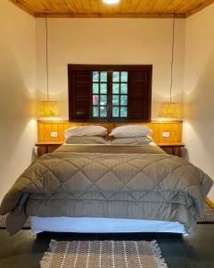 a bedroom with a bed with a window and two lamps at Rancho do Paioleiro - Suites in São Bento do Sapucaí