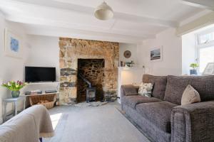 a living room with a couch and a stone fireplace at Finest Retreats - Coral Cottage in Porthleven