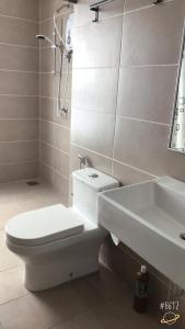 een witte badkamer met een toilet en een wastafel bij D'sara Sentral Sovo in Sungai Buluh