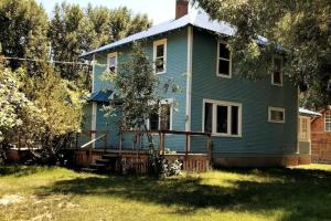 ein blaues Haus mit einer Terrasse im Hof in der Unterkunft Spacious Farmhouse with Pond in Augusta