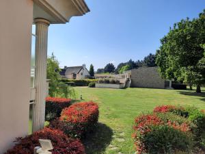 un cortile con fiori rossi e una casa di Appartement de standing dans le Golf International de La Baule a Saint-André-des-Eaux