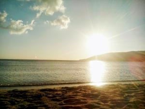 uma praia com o sol brilhando sobre a água em Andros Studios Tetrafylli em Andros