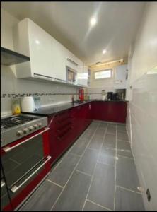 - une cuisine avec des placards rouges et une cuisinière dans l'établissement Chambre Serenity, à Stains