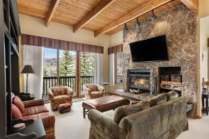 uma sala de estar com uma grande parede de pedra e uma lareira em 229 Faraway The Ridge #35 condo em Snowmass Village