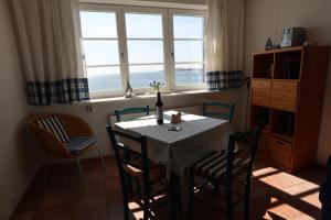 comedor con mesa, sillas y ventanas en Ferienwohnung Soling, en Alt Reddevitz