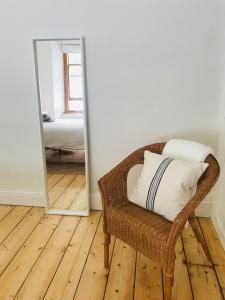 a wicker chair with a pillow in front of a mirror at Harbour House Looe in Looe