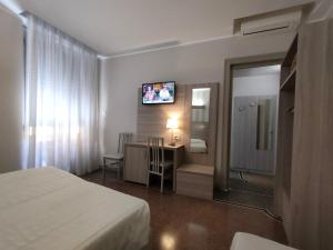 ジェノヴァにあるホテル ヴィットーリアのベッドとテレビが備わるホテルルームです。