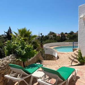 a couple of lawn chairs and a swimming pool at Casa do Milho in Carvoeiro