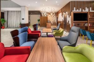 a lobby with colorful chairs and tables and a tv at Park Inn by Radisson Jeddah Madinah Road in Jeddah