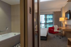 
a hotel room with a large tub and a large window at Radisson Blu Gautrain Hotel, Sandton Johannesburg in Johannesburg
