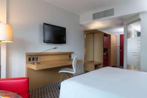 a hotel room with a television and a bed at Radisson Blu Gautrain Hotel, Sandton Johannesburg in Johannesburg