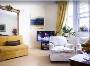 een woonkamer met een stoel en een televisie bij KNIGHTSBRIDGE early AM check-in often possible -Next2 HARRODS 3 BEDROOMS-2Baths in Londen
