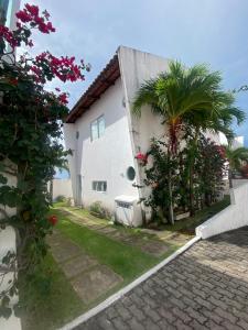 a white house with a palm tree next to it at Casa em Condomínio, Aquiraz - CE in Aquiraz