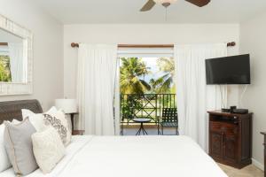 a bedroom with a bed with a television and a balcony at Villa Montaña Beach Resort in Isabela