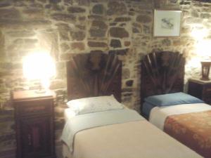 2 camas en una habitación con una pared de piedra en B&B Borgo del Fornello, en San Benedetto Val di Sambro