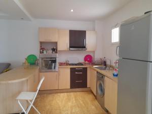 a kitchen with wooden cabinets and a white refrigerator at Playa del Pasha in Restinga Smir