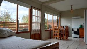 a bedroom with a bed and a kitchen with windows at ROCA AZUL in El Bolsón