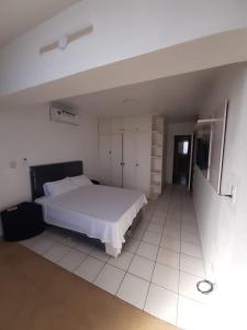 ein Schlafzimmer mit einem weißen Bett und einem weißen Fliesenboden in der Unterkunft Departamento en el centro de la ciudad in Encarnación
