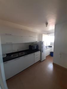 a white kitchen with a refrigerator and a sink at Departamento en el centro de la ciudad in Encarnación