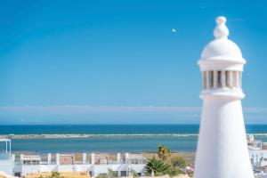a lighthouse in front of the ocean and buildings at LV Premier Algarve FU1- pool, AC, garden, sea view in Moncarapacho