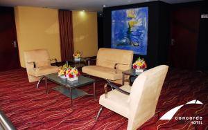 een wachtkamer met stoelen en tafels en een schilderij bij Hotel Concorde Toluca in Toluca