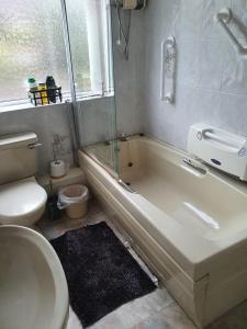 a bathroom with a tub and a toilet and a sink at ABIMDOT Exquisite apartments in Manchester