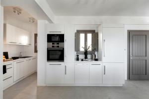 ピルゴスにあるEolia Luxury Villasの白いキッチン(白いキャビネット、電化製品付)