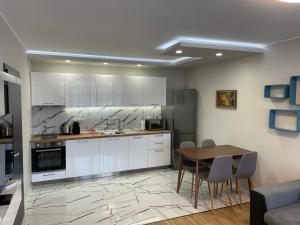 a kitchen with white cabinets and a table and chairs at SEA GARDEN PANORAMA APARTMENT in Burgas