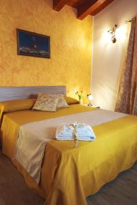 a yellow bedroom with a bed with two towels on it at Agriturismo Bella Vista - Da Carmelo in Santa Teresa di Riva
