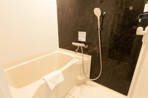 a bath tub in a bathroom with a shower at Henn na Hotel Tokyo Haneda in Tokyo