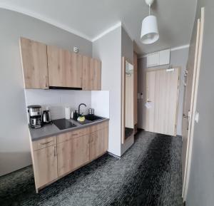 uma cozinha com armários de madeira e um lavatório em Cesarskie ogrody 102A By Edyta em Świnoujście