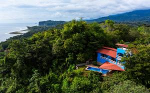 a blue house on a hill next to the ocean at El Paraiso Azul in Ojochal +20 photos