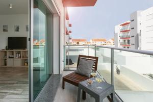 a balcony with a chair and a table with wine glasses at SURFERS PARADISE in Peniche