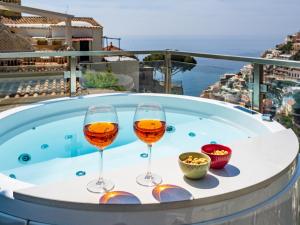 Dwa kieliszki wina siedzące w wannie z hydromasażem w obiekcie Santoro Suite w mieście Positano