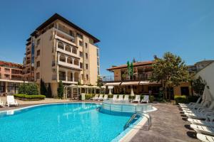 a large swimming pool with chairs and a building at Rose Village - Private apartment - BSR - 1 in Sunny Beach