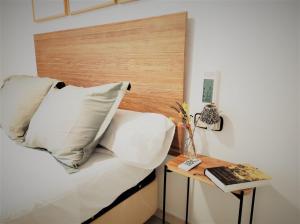 ein Bett mit weißen Kissen und einem Kopfteil aus Holz in der Unterkunft Lovely apartment in Calafell