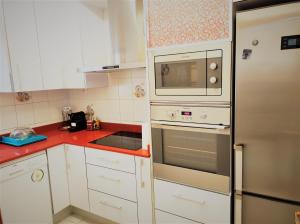 eine Küche mit weißen Schränken und einem Kühlschrank aus Edelstahl in der Unterkunft Lovely apartment in Calafell
