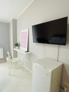 ein Wohnzimmer mit einem TV und einem weißen Kühlschrank in der Unterkunft Sicily Emotion in Giardini-Naxos