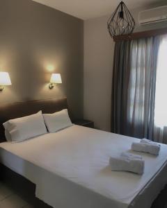 a bedroom with a large white bed with two towels on it at Fenareti Apartments in Skala Eresou