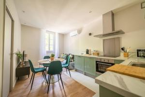 a kitchen with green cabinets and a table and chairs at Le Pearl Appartement de charme en bord rivière in Collobrières